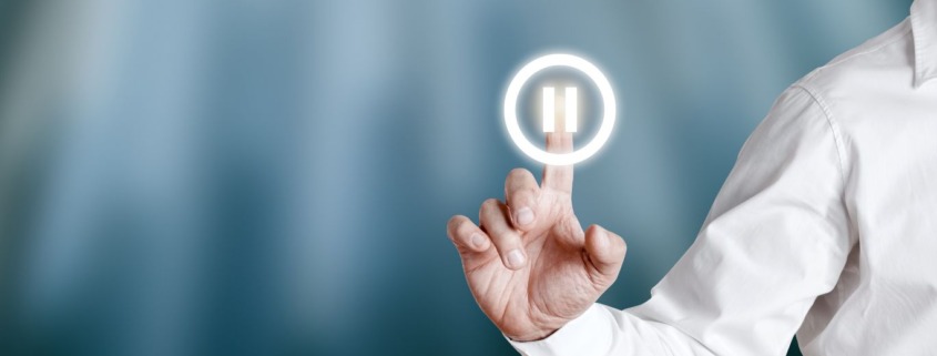 Hand pressing pause button, symbolizing the power of pausing to shift habits